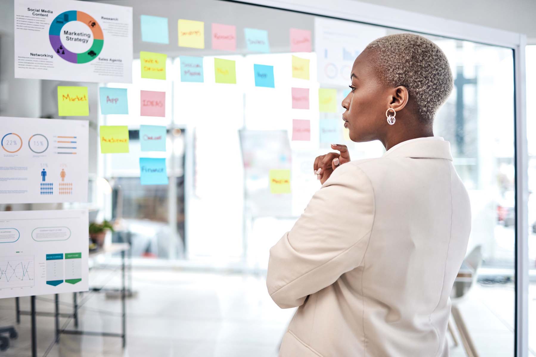 Black woman, thinking and glass board for project management, marketing or planning at office. African female person, manager or employee checking project plan, tasks or statistics at the workplace